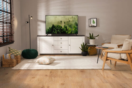 Natural oak wide plank hardwood flooring from Rustic Wood Floors Supply in a living room setting, showcasing a modern entertainment area with a flat-screen TV, white cabinet, and comfortable seating, emphasizing the flooring's warm, natural look