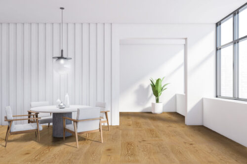 Light oak wide plank flooring in a modern dining room, featuring a round table, four chairs, a pendant light, and a potted plant, showcasing the flooring's natural wood grain and suitability for a bright, minimalist space.